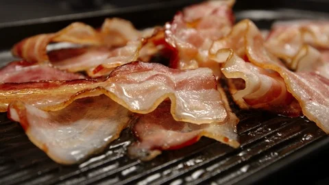 CLOSE UP: Heap of fried strips of bacon on a pan Stock Footage 94443578