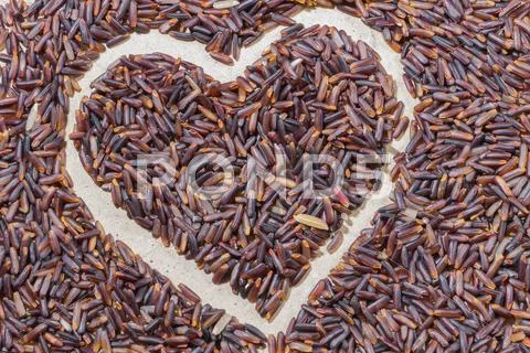Close-up heart shape brown rice on wooden background Stock Photos