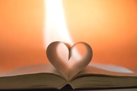 Close up of heart shape of open hardback book, copy space, soft yellow orange Stock-Fotos