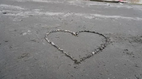 Close-up of a heart shape outlined in small pebbles on concrete surface. Stock Photos
