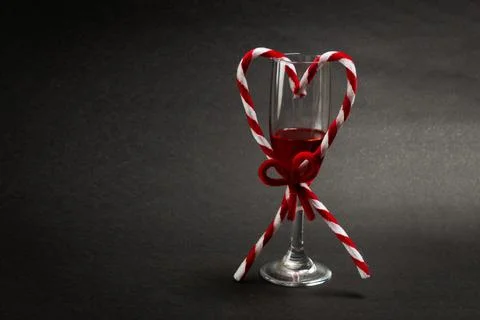 Close-up of heart shaped candy cane with red wine glass on table Stock Photos
