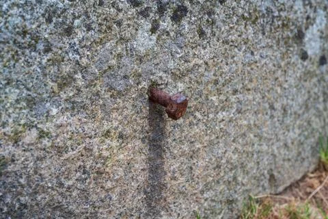 Close up of a heavily rusted bolt embedded in a textured stone surface Stock Photos