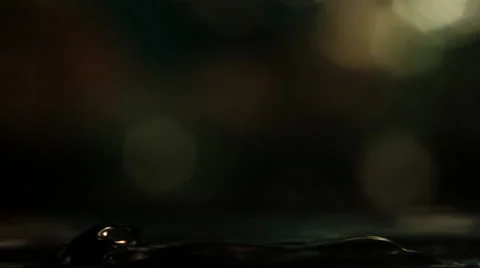 Close-up of heaving dark water receiving ultra-slow motion rebounding drops Stock Footage 59527583