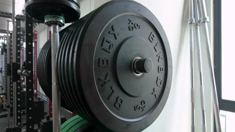 Close-up of a heavy barbell loaded with multiple weight plates in a modern gym. 库存影片 333876757