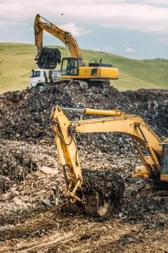 Close up of heavy duty excavators loading dumper trucks with garbage Stock Photos