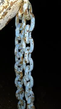 Close-up of heavy old rusty metal chain links painted blue hanging against so 스톡 사진