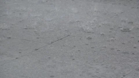Close-Up heavy rain falling on grey stone pavement creating water ripples Stock Footage 342241111