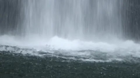 Close up of heavy waterfall curtain hitting turbulent water surface Stock Footage 325577920