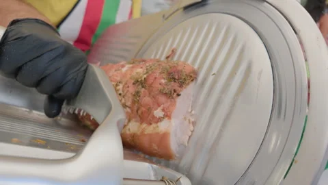 Close-up of a herb-crusted cured meat being sliced on a deli slicer at a market Stock Footage 344828582
