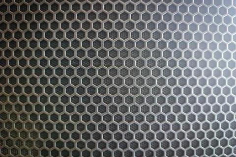 A close-up of a hexagonal honeycomb pattern on a dark textured surface. Stock Photos