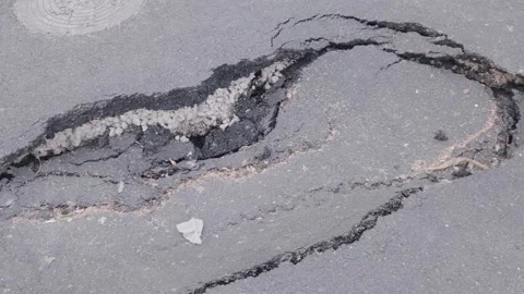 Close up high angle shot of a large dangerous pothole and cracked collapsed Stock Footage 345203058
