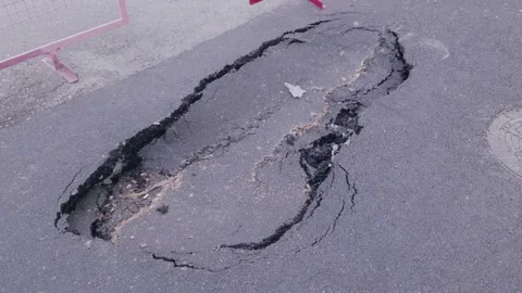 Close up high angle shot of a large dangerous pothole and cracked collapsed Stock Footage 345206029