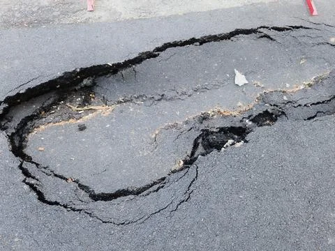 Close up high angle shot of a large dangerous pothole and cracked collapsed.. Stock Photos