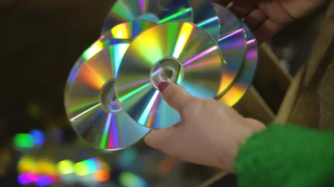 Close-up high angle view female hands throwing compact discs in box indoors in Stock Footage 248971772