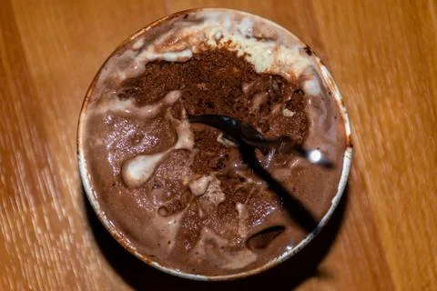 A close-up high angle view of a small bucket of melting chocolate ice cream w Stock Photos