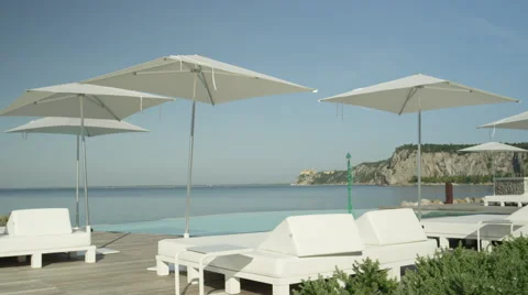 CLOSE UP: High class oceanfront hotel with daybed loungers and infinity pool Stock Footage 68721192