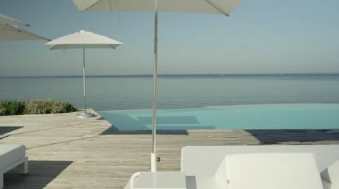 CLOSE UP: High class oceanfront resort with daybed loungers and infinity pool Stock Footage 68721059