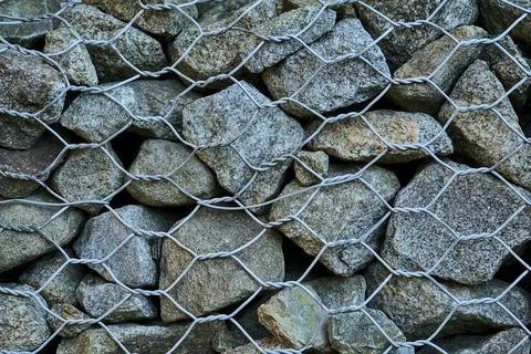 Close up high resolution view of gabion wall rocks and stones in metal wire box Stock Photos