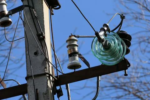 Close-up of high-voltage power lines and power pylons against a blue sky. Stock Photos