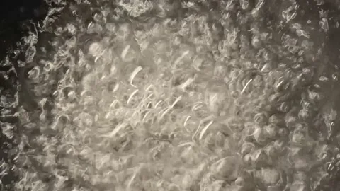 A close-up of highly boiling water with large bubbles. Video stock 150242721