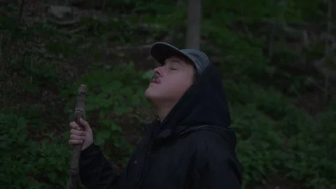 Close-up of a hiker holding a walking stick and looking up in a dense... Видео 336190367