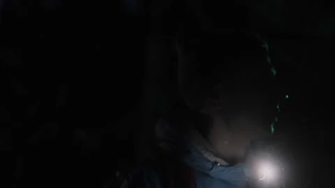 Close-up of a hiker navigating the dark forest at night, using a flashlight to Stock Footage 311453727