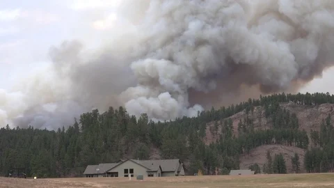 CLOSE UP: Hill fire burning and smoke rising from behind a idyllic country house Stock Footage 74940639