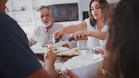Close up of Hispanic family sitting at the table serving food at a family meal, Stock Footage