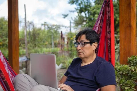 Close-up of a Hispanic man with glasses working remotely on a laptop from a Foto stock