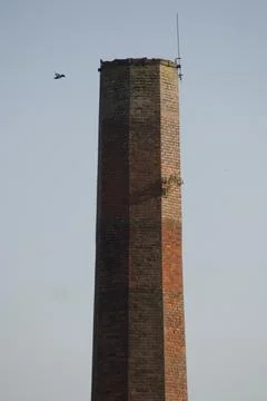 Close-up of a historic octagonal brick mill chimney stack against a clear sky. Stock Photos