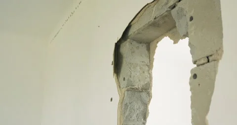 Close-up of a hole in a wall where a man is hitting it with a hammer. Demolition Stock-Footage 219724622