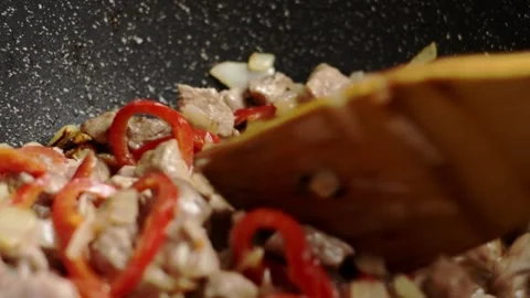 Close-Up of Home Cook Stirring Fried Meat, Red Bell Pepper, and Onion Stock Footage 256602976