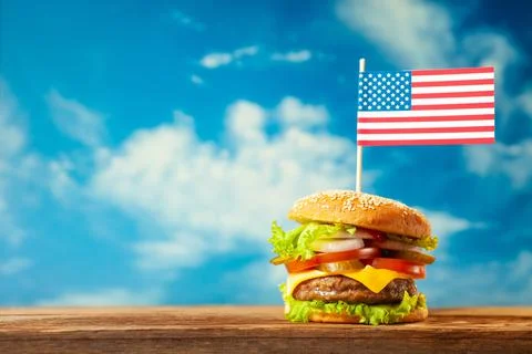 Close-up home made beef burger with american flag on the top on wooden table  Stock Illustration
