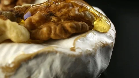 Close-up honey flows through walnut and camembert cheese slow motion Video stock 104981649