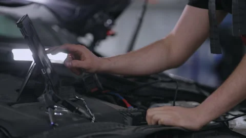 Close-up at the hood of the car a mechanic with a tablet presses the screen to Stock Footage 166442425