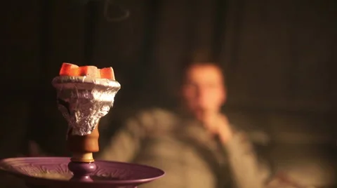Close-up of hookah coals. A man smokes a hookah in the background Stock Footage 64701902