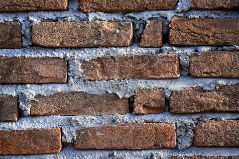 A close-up horizontal shot of a textured red brick wall with thick, rough c.. Stock Photos