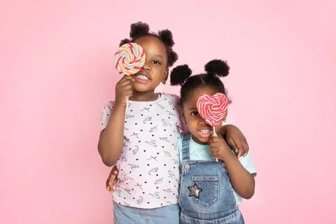 Close up horizontal shot of two cute little African girls covering her eyes with 库存照片