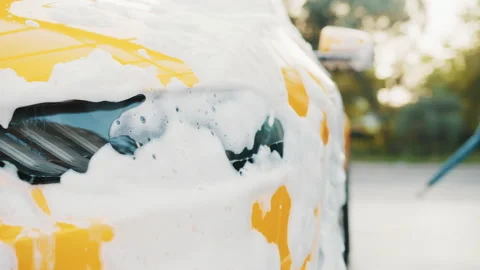 Close up horizontal shot of yellow car headlight with cleaning foam, washed at Stock Footage 171664719