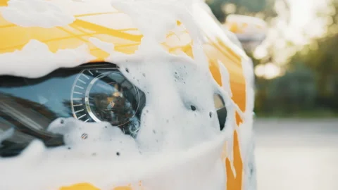 Close up horizontal shot of yellow car headlight with cleaning foam, washed at Stock Footage 171666162