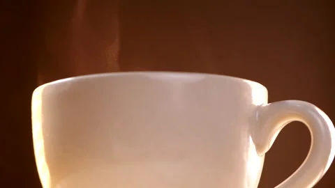 Close-up of hot coffee cup steaming in slow motion on brown background Stock Footage 140296547