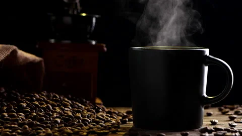 Close-up hot coffee cup with steaming smoke, coffee grinder and coffee beans Stock Footage 205058224