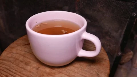 Close-up: a hot cup of ginger tea with honey on a table by the fireplace. A mug Stock Footage 338134940