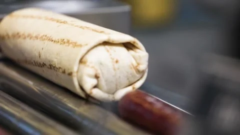 Close-up of a hot dog wrapped in lavash being cooked on a grill at a gas sta Stock Footage 335247530