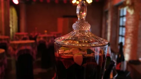 Close up hot red mulled wine in a glass jug. Blurry lights on black background.  Stock Footage 233513433