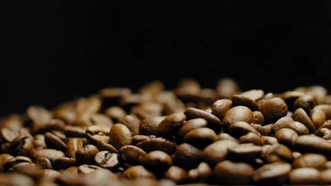 Close-up of hot roasted coffee beans falling down against a black background. Stock Footage 295673744