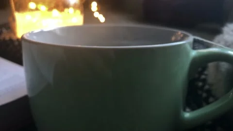 Close- Up of Hot Steaming Cup of Tea Next to an Open Book Vídeo Stock 100696717
