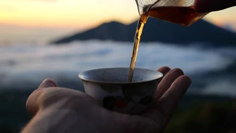 Close-up of hot tea being poured into a tiny porcelain cup in mountains above Stock Footage 255472043
