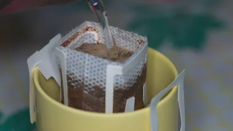 Close-up of Hot Water Being Poured Into a Convenient Drip Coffee Filter Bag Stock Footage 339630265