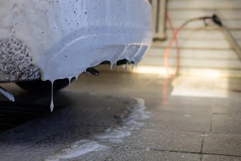 Close-up of how foam flows and drips onto the floor from the car during a wash Stock Photos
